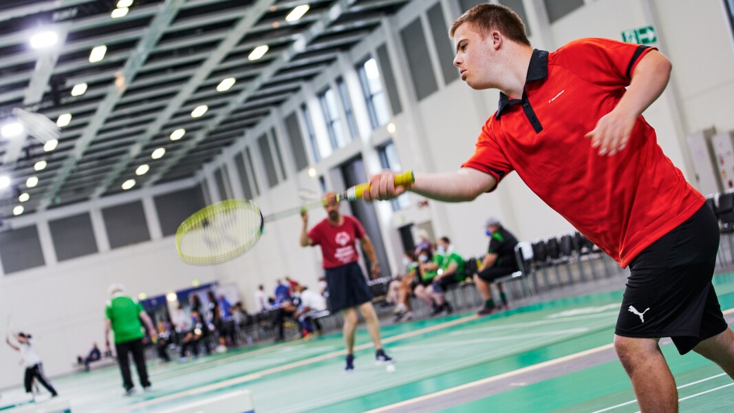 The photo shows a scene at badminton. The male athlete is performing a stroke.