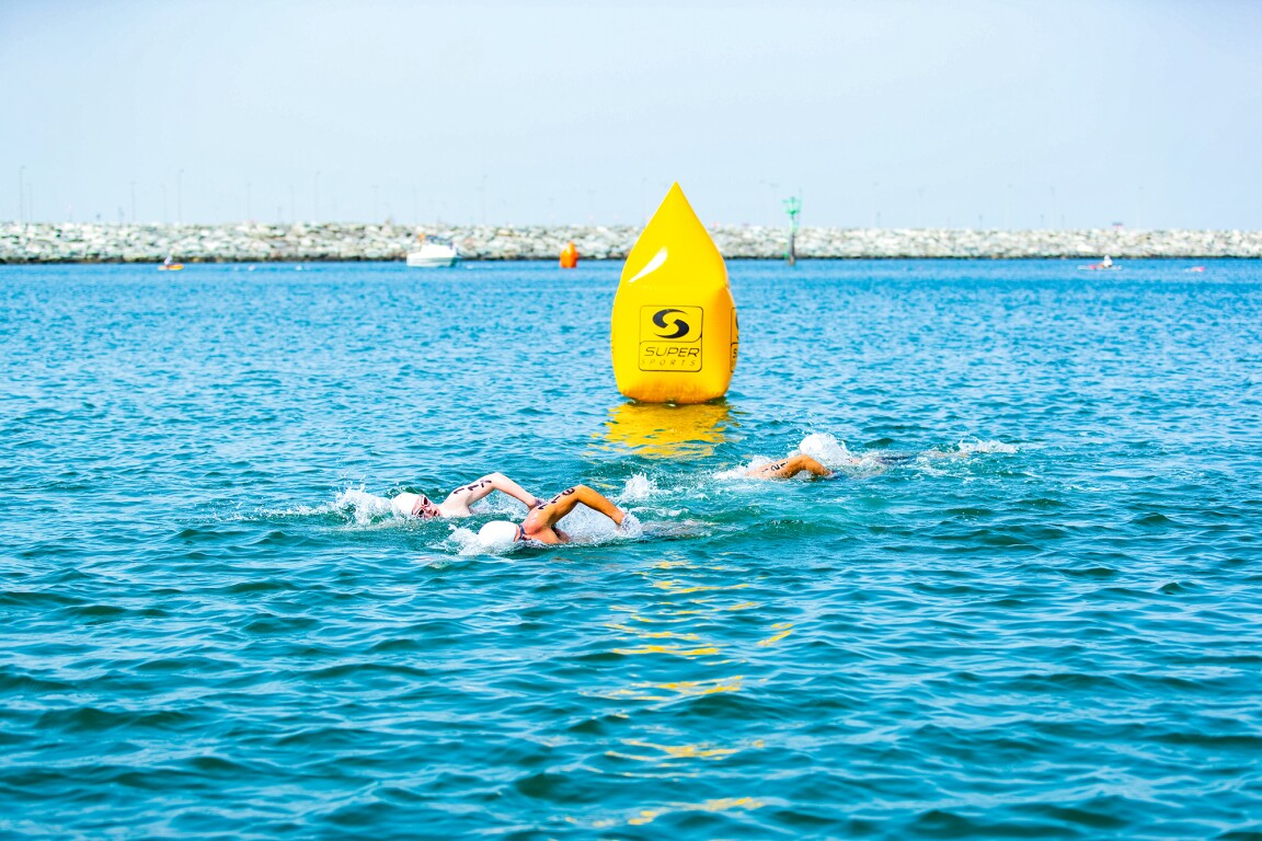 Das Foto zeigt drei Schwimmer*innen beim Freiwasserschwimmen.
