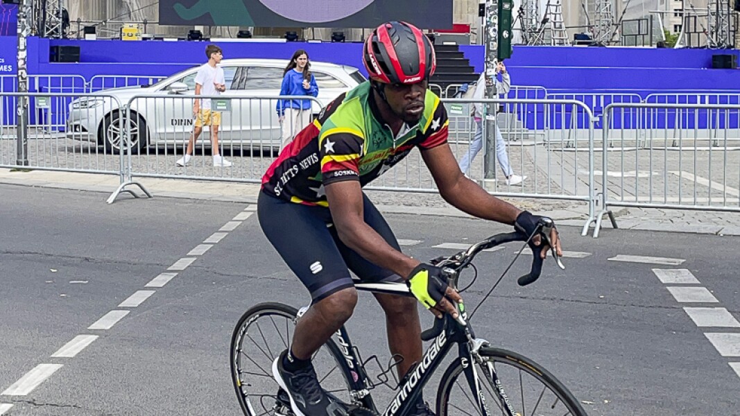 Auf dem Foto ist ein Athlet zu sehen der auf dem Fahrrad fährt. Er schaut konzentriert aus.