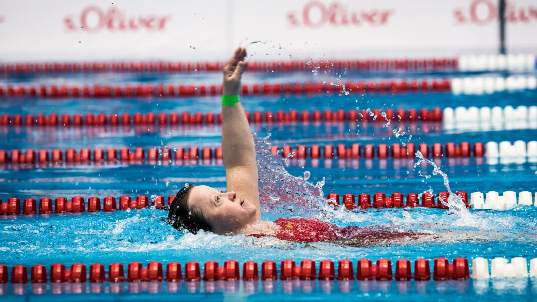 Das Foto zeigt eine Schwimmerin während des Wettbewerbs im Becken. Sie ist gerade dabei im Rückenschwimmen anzutreten.