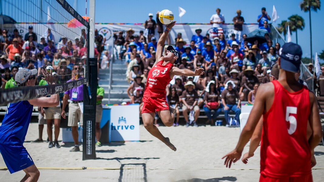 Auf dem Foto ist eine Spielszene beim Beachvolleyball mit mehreren Spielern zu sehen.