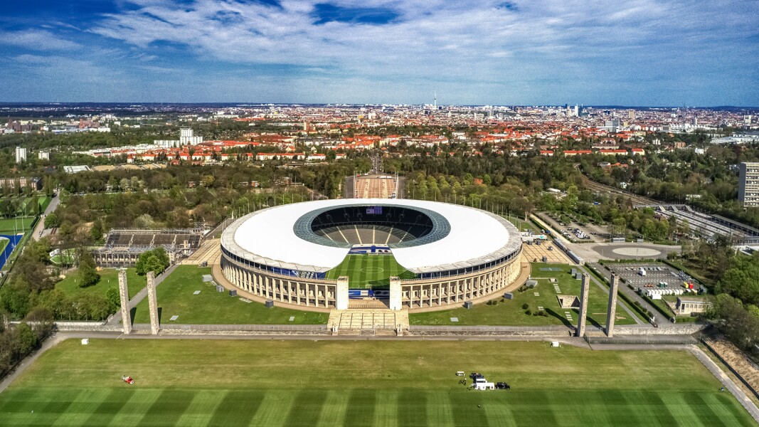 Das Foto zeigt das Berliner Olympiastadion und dahinter liegende Häuser aus der Vogelperspektive.