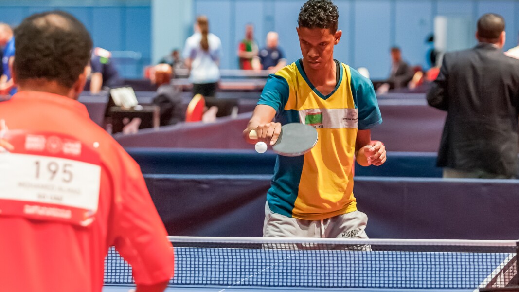 Das Foto zweigt zwei Spieler beim Tischtennis. Ein Spieler ist sehr konzentriert und spielt gerade den Ball übers Netz.