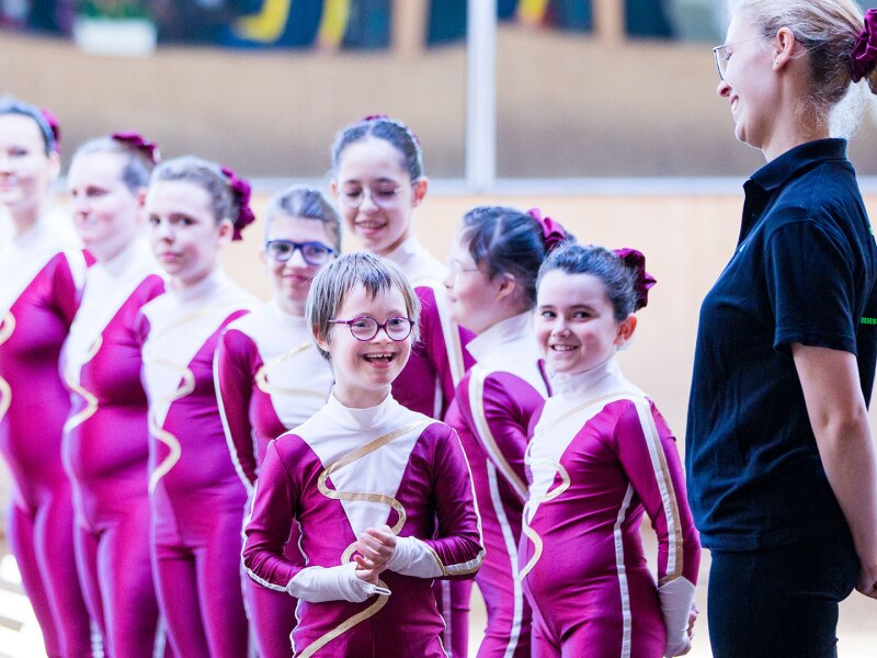 Auf dem Foto ist eine Gruppe Mädchen mit Trainerin zu sehen. Sie sind ein Voltigier-Team, das bei den Nationalen Spielen in Berlin anstritt. Ganz vorne lächelt Judith Sonnenschein.