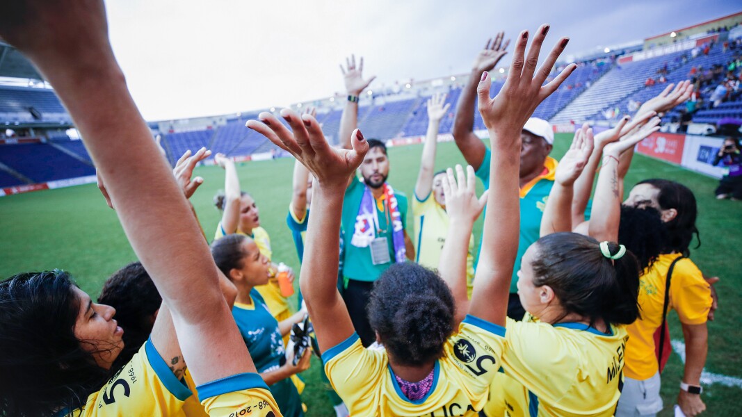 Auf dem Foto sieht man Athletinnen einer Frauenmannschaft, die die Arme in die Luft reißen und jubeln.