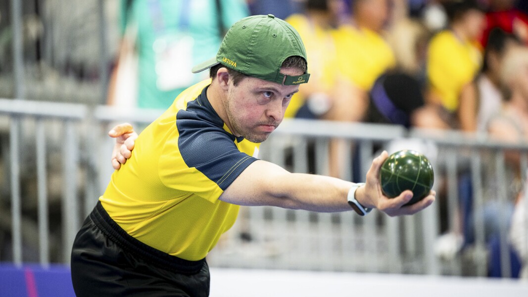 The photo shows an athlete playing bocce. He looks very concentrated.