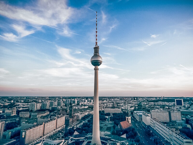 The photo shows the Fernsehturm (Berlin TV tower) in front of the panorama of the city and against a picturesque blue sky.