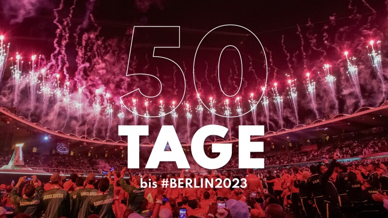 Auf dem Foto sind viele Menschen und Feuerwerk zu sehen. Und der Schriftzug 50 Tage bis #Berlin2023