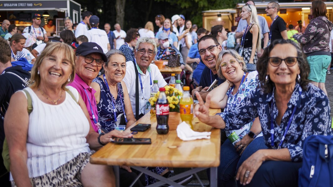 Das Foto zeigt eine Gruppe Menschen, die an einem Tisch beisammen sitzen und freudig lächeln. Es ist die Familie eines Athleten, die zu den Nationalen Spielen angereist ist.