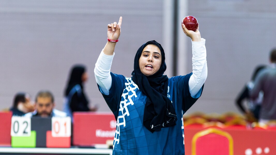 Das Foto zeigt eine Boccia-Spielerin, die eine Kugel in der Hand hochhält und jubelt.