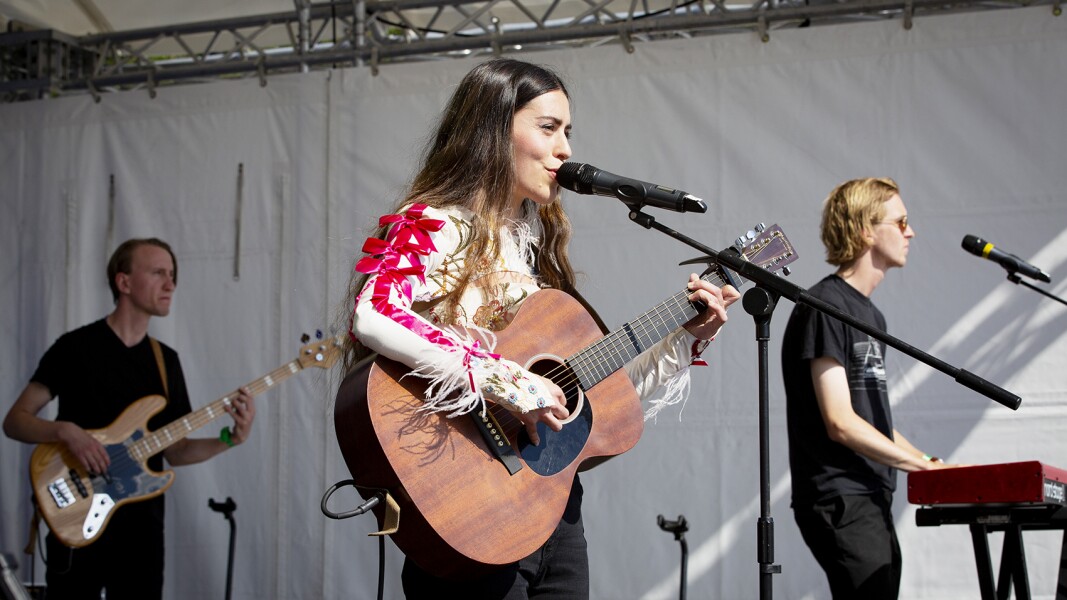 Das Foto zeigt eine Band, die auf dem Special Olympics Festival 2022 auftritt. Im Vordergrund ist die Sängerin zu sehen, die mit ihrer Gitarre auf der Bühne steht.