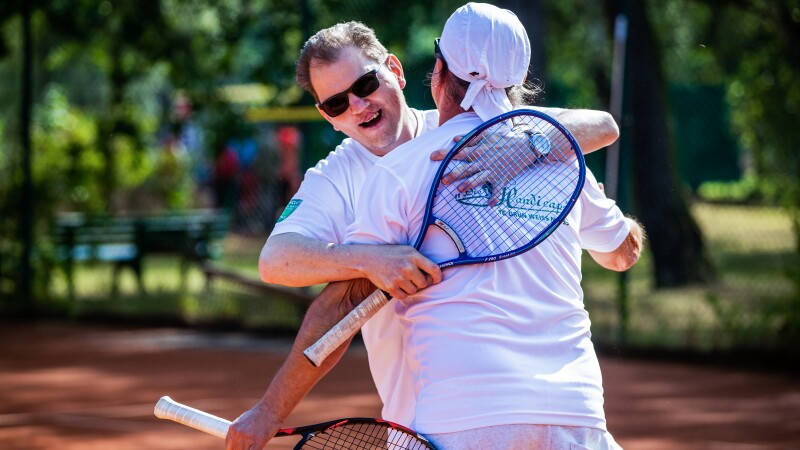 The photo shows two athletes playing tennis, just while they are hugging each other joyfully.