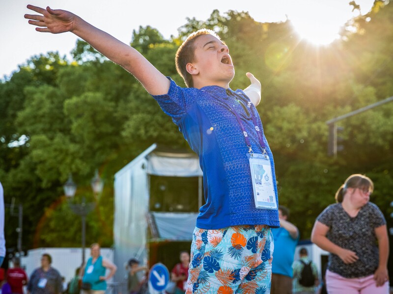 On the picture an athlete is enjoying. He holds both arms straight into the air, his eyes are closed and he is singing. In the background you see further people celebrating.