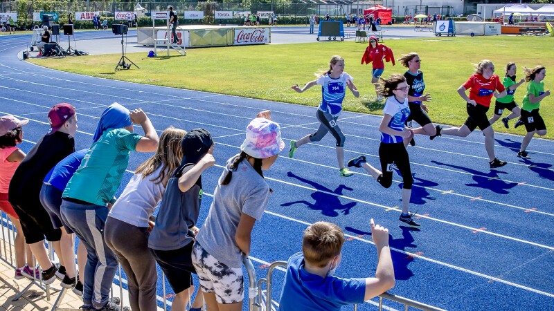 The photo shows a scene in athletics. Students from the Inclusive Campus Spandau cheer on the athletes during their race. They participated in the "Fans in the Stands" program.