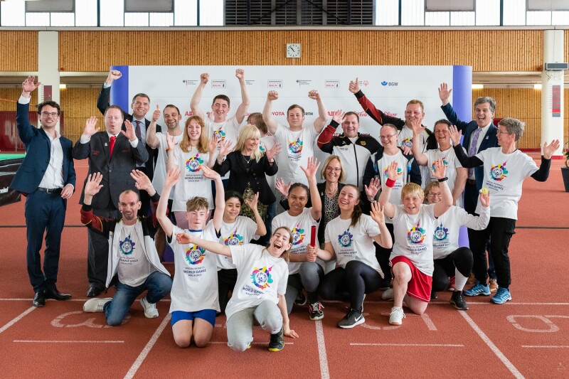 The photo shows all participants of the press conference, among other many athletes, Sven Albrecht, Timothy Shriver and Ian Harper. Everyone has their arms raised in joy.