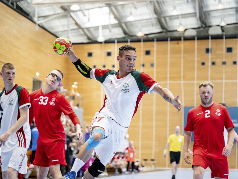 Das Foto zeigt eine Szene aus dem Handballspiel, bei der ein ungarischer Spieler im weißen Trikot gerade mit fast ausgestrecktem Arm zum Wurf ansetzt.