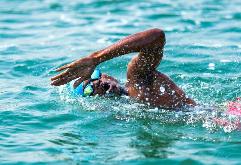 The photo shows an athlete during an open water swimming competition.