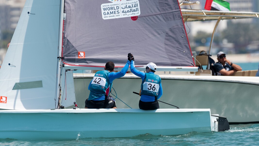 Zwei Segler geben sich ein Highfive auf ihrem Segelboot.
