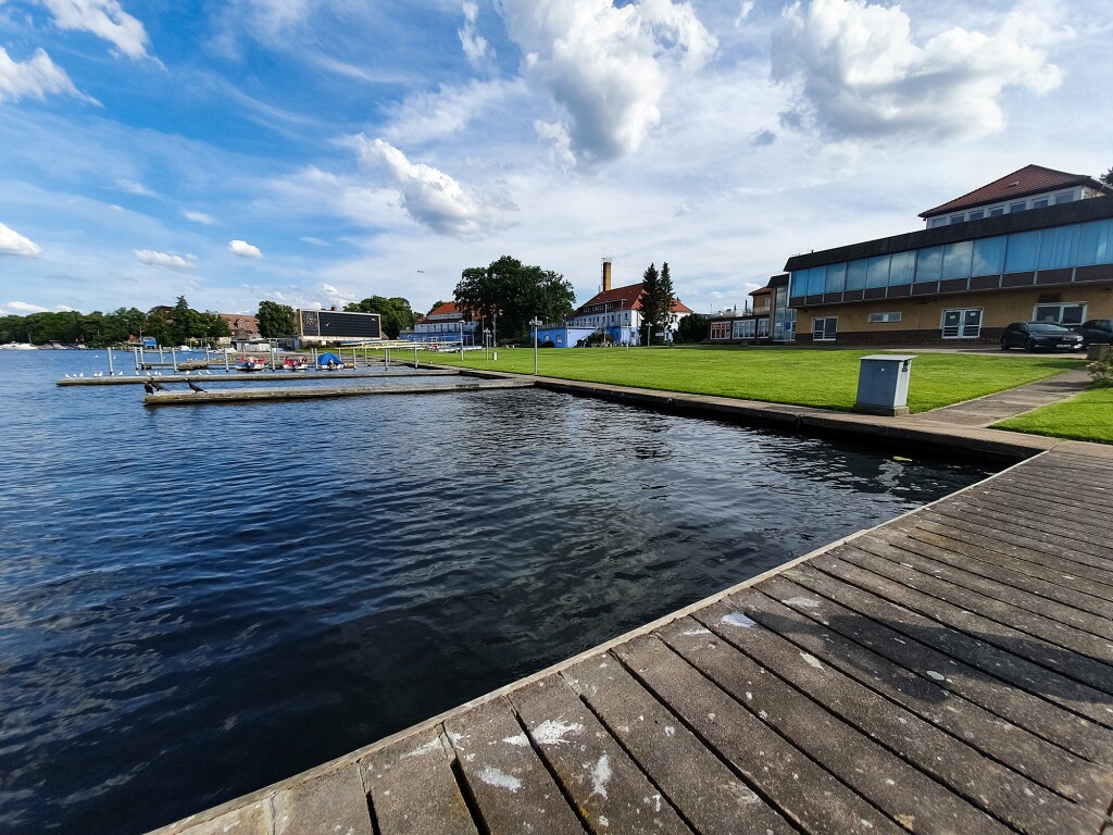 Das Foto zeigt mehrere Stege die ins Wasser reichen und im Hintergrund einige kleinere Gebäude.