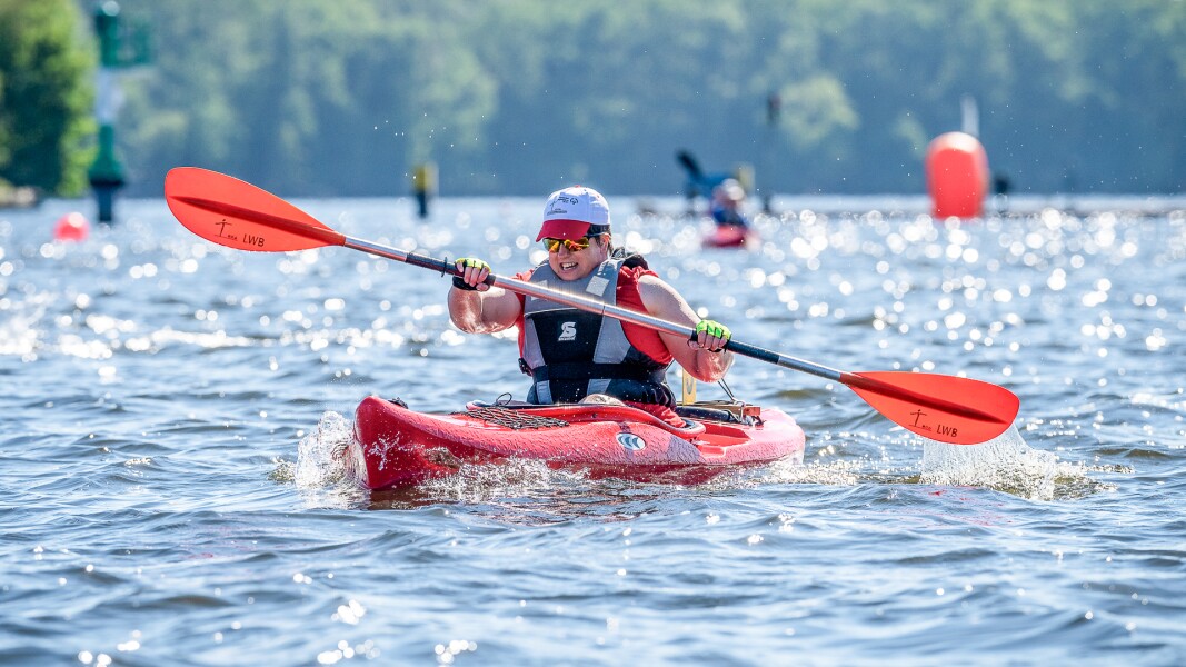 Auf dem Foto sieht man eine Athletin in ihrem Kajak auf dem Wasser in Aktion.