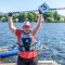 The photo shows kayakist Juliana Rößler after winning the kayaking race during the Special Olympics National Games Berlin 2022, holding her paddle above her head in jubilation.