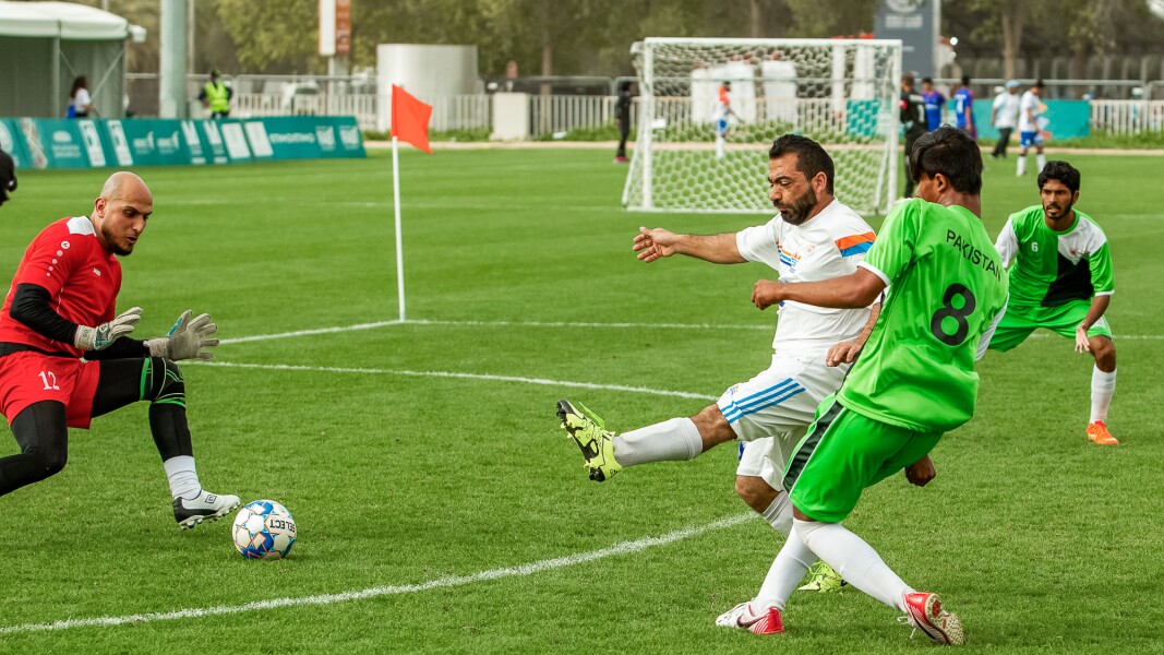 Das Foto zeigt zwei Mannschaften beim Futsal. Ein Spieler schießt auf das Tor. Der Torwart pariert den Schuss.