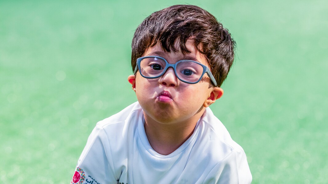 Das Foto zeigt einen kleinen Jungen mit Brille. Er formt mit seinen Lippen einen Kussmund.