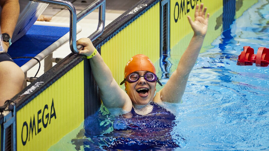 Das Foto zeigt eine spanische Schwimmerin im Ziel des Schwimmbeckens. Mit einer Hand hält sie sich am Startblock fest während sie mit der anderen Hand jubelt. Sie sieht sehr glücklich dabei aus!