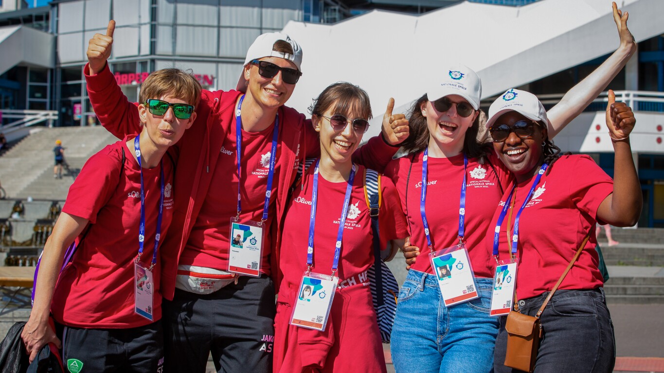 Auf dem Foto ist eine Gruppe von 5 Volunteers beim SO Festival zu sehen. Sie jubeln in die Kamera und haben sichtlich Spaß.