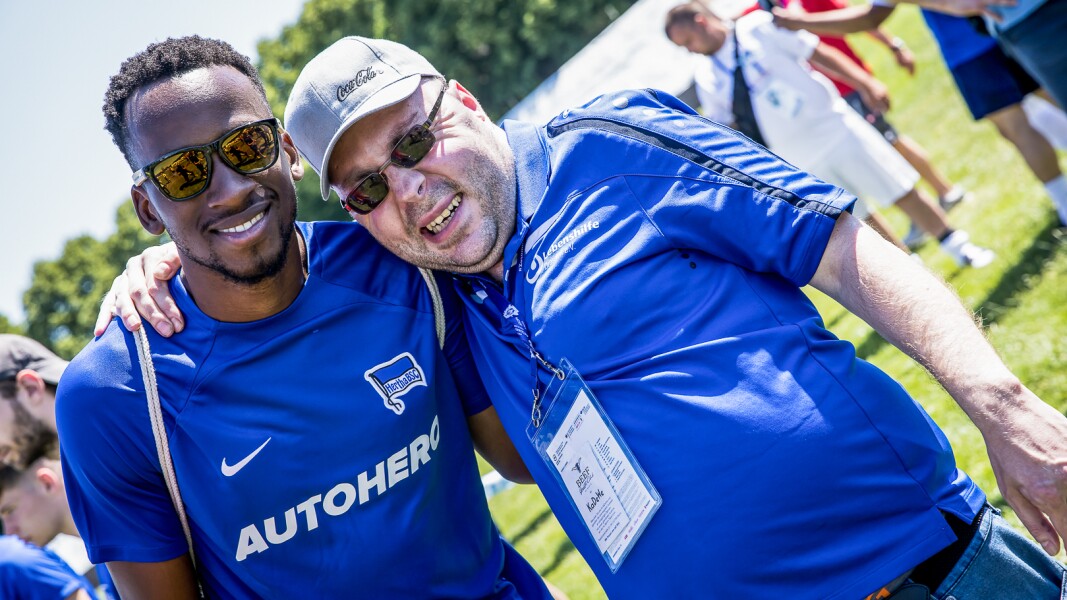 The photo shows a Hertha professional soccer player and an athlete taking a photo together and both smiling at the camera.