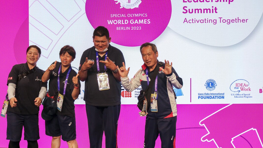 The photo shows a tandem from Japan at the Global Youth Leadership Summit. They are holding up their hands and laughing.