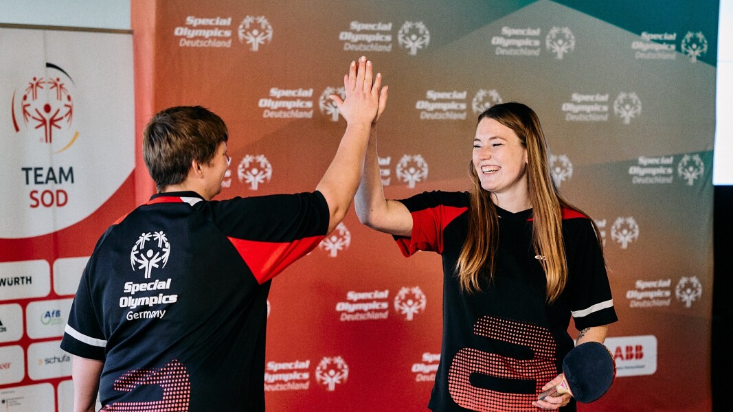 Das Foto zeigt zwei Frauen, die gemeinsam als Unified Doppel im Tischtennis antreten. Während das Bild aufgenommen wurden, haben sich die beiden ein High Five gegeben, nachdem sie den Punkt im Spiel gemacht haben.