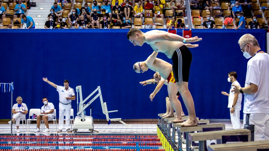Das Foto zeigt eine Szene beim Schwimmen, kurz bevor die Athleten vom Startblock in das Wasser springen.