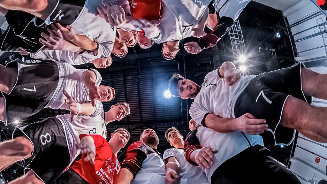 Das Foto ist von unten und in der Mitte des Mannschafts-Kreises aufgenommen. Die Volleyball-Spieler feuern sich gegenseitig an.