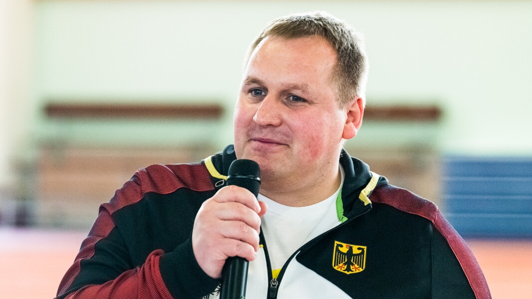 Auf dem Foto ist Athletensprecher und LOC-Mitarbeiter Dennis Mellentin zu sehen, der gerade in ein Mikrofon spricht.