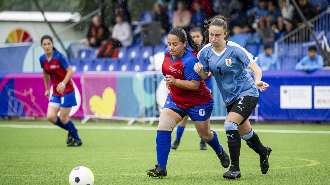 The photo shows two female futsal players in action. They are in a duel for the ball.