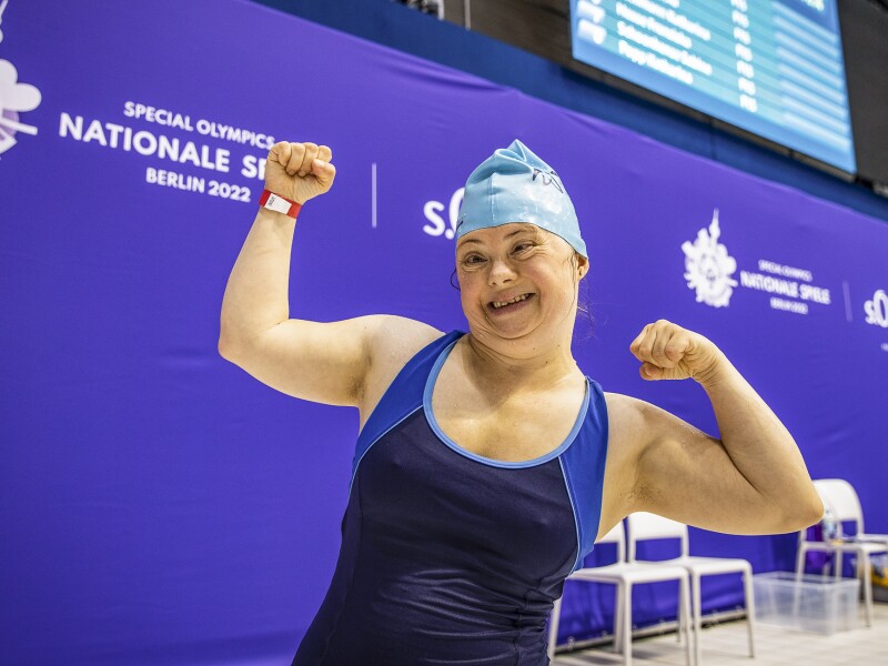 The photo shows athlete Anna Wyrzgol from Special Olympics Lower Saxony. She is happy, raises her arms and smiles at the camera.