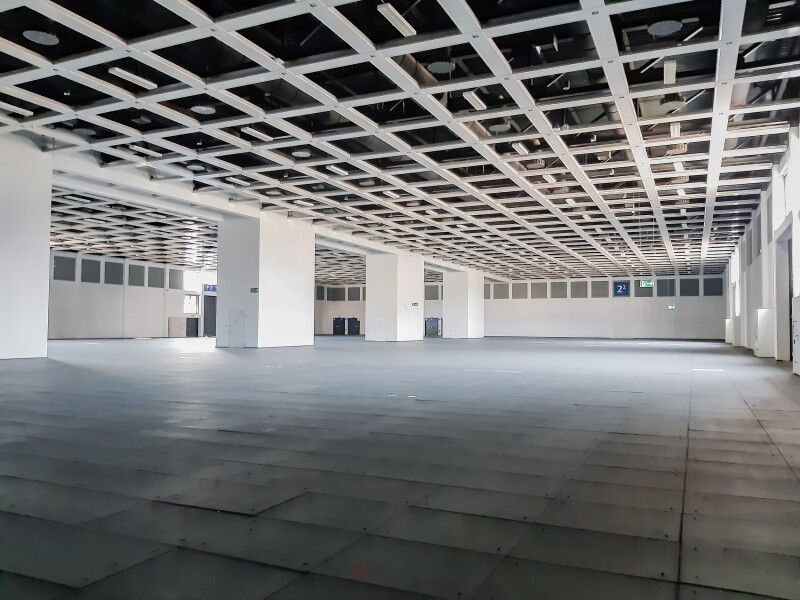 The photo shows the interior view of a large sports hall with wide white columns.