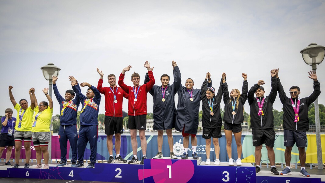 The photo shows a cheering scene during the award ceremony at the open water swimming. Everyone looks happy and has their arms raised in the air.