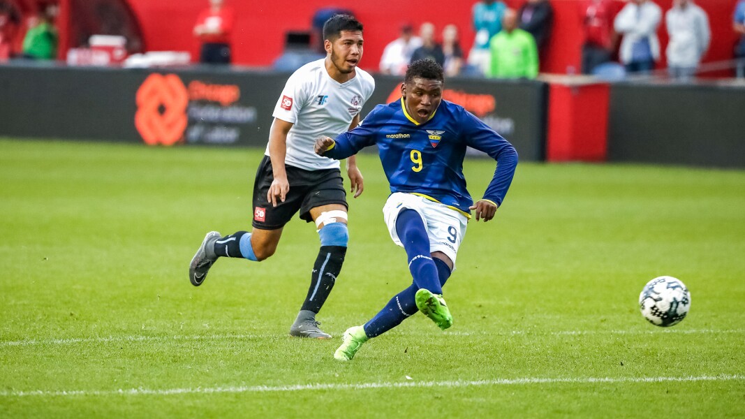Das Foto zeigt zwei Fußballspieler aus zwei verschiedenen Mannschaften. Ein Spieler spielt einen Pass.