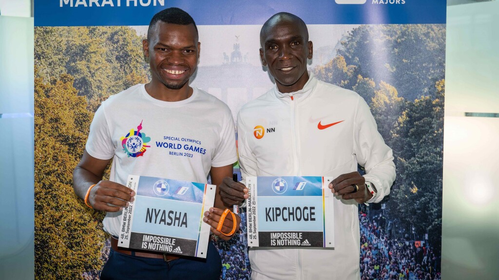 Auf dem Foto halten Special Olympics International Global Messenger und Langstreckenläufer Nyasha Derera und Olympiasieger und Vorbild Eliud Kipchoge ihr jeweiliges Marathon-Namensschild lächelnd in die Kamera.