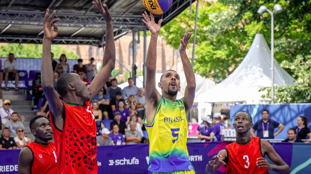 The Brazilian athlete wearing yellow jersey is trying to shoot the ball while three Kenyan athletes wearing the red jersey is trying to block the shot