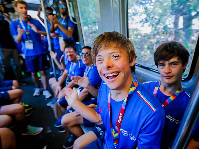 The photo shows athletes of the Italian delegation on a train. They laugh into the camera and are happy.