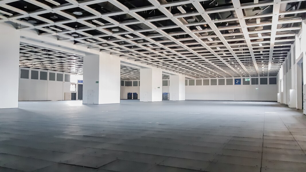 Das Foto zeigt die Innenansicht einer großen Sporthalle mit breiten, weißen Säulen.