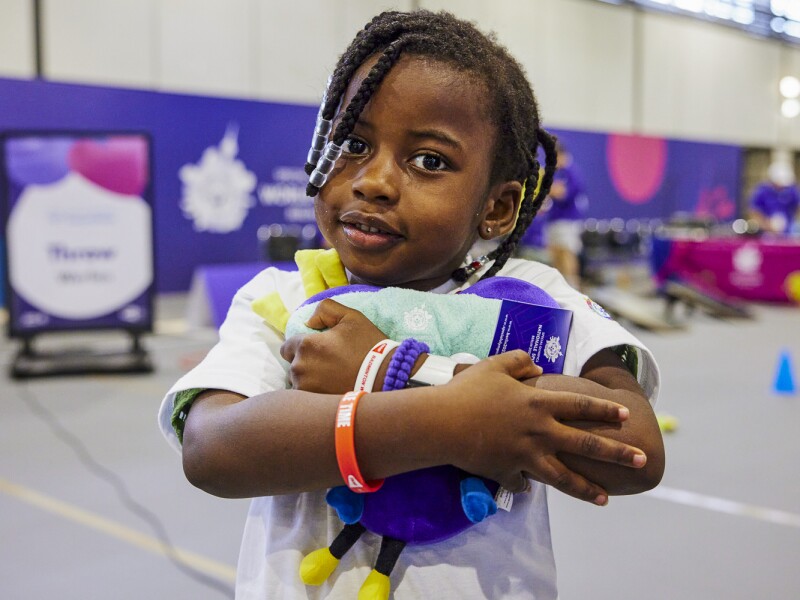 The photo shows a little girl who participated in the Young Athletes program during the World Games in Berlin, holding a plush Unity in her arms.