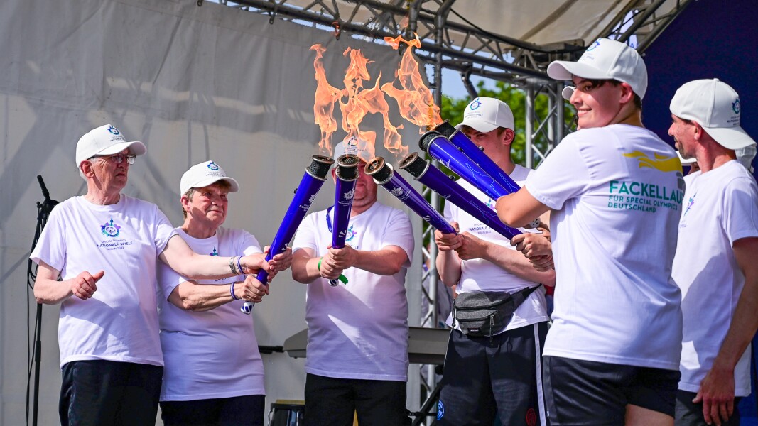 In the picture there is a group of people, each holding a torch up and together. It is the ceremony where the torches of the national federations are united into the one flame of the National Games.