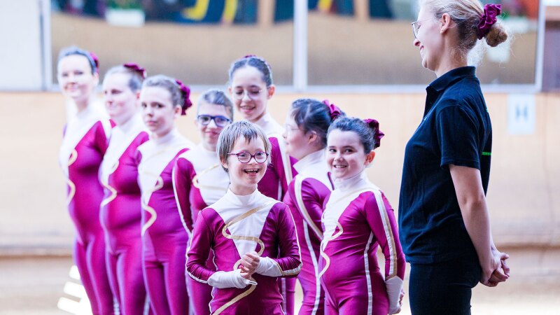 Auf dem Foto ist eine Gruppe Mädchen mit Trainerin zu sehen. Sie sind ein Voltigier-Team, das bei den Nationalen Spielen in Berlin anstritt. Ganz vorne lächelt Judith Sonnenschein.