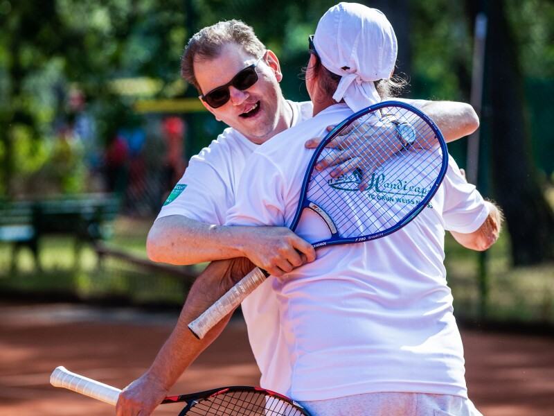 The photo shows two athletes playing tennis, just while they are hugging each other joyfully.
