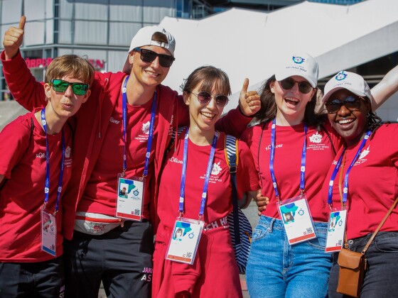 The photo shows a group of 5 volunteers at the Special Olympics Festival during the National Games. They are cheering into the camera and visibly having fun.