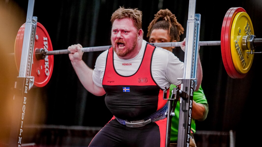 Das Foto zeigt einen Athleten beim Kraftdreikampf. Er hat einen knallroten Kopf und schreit.